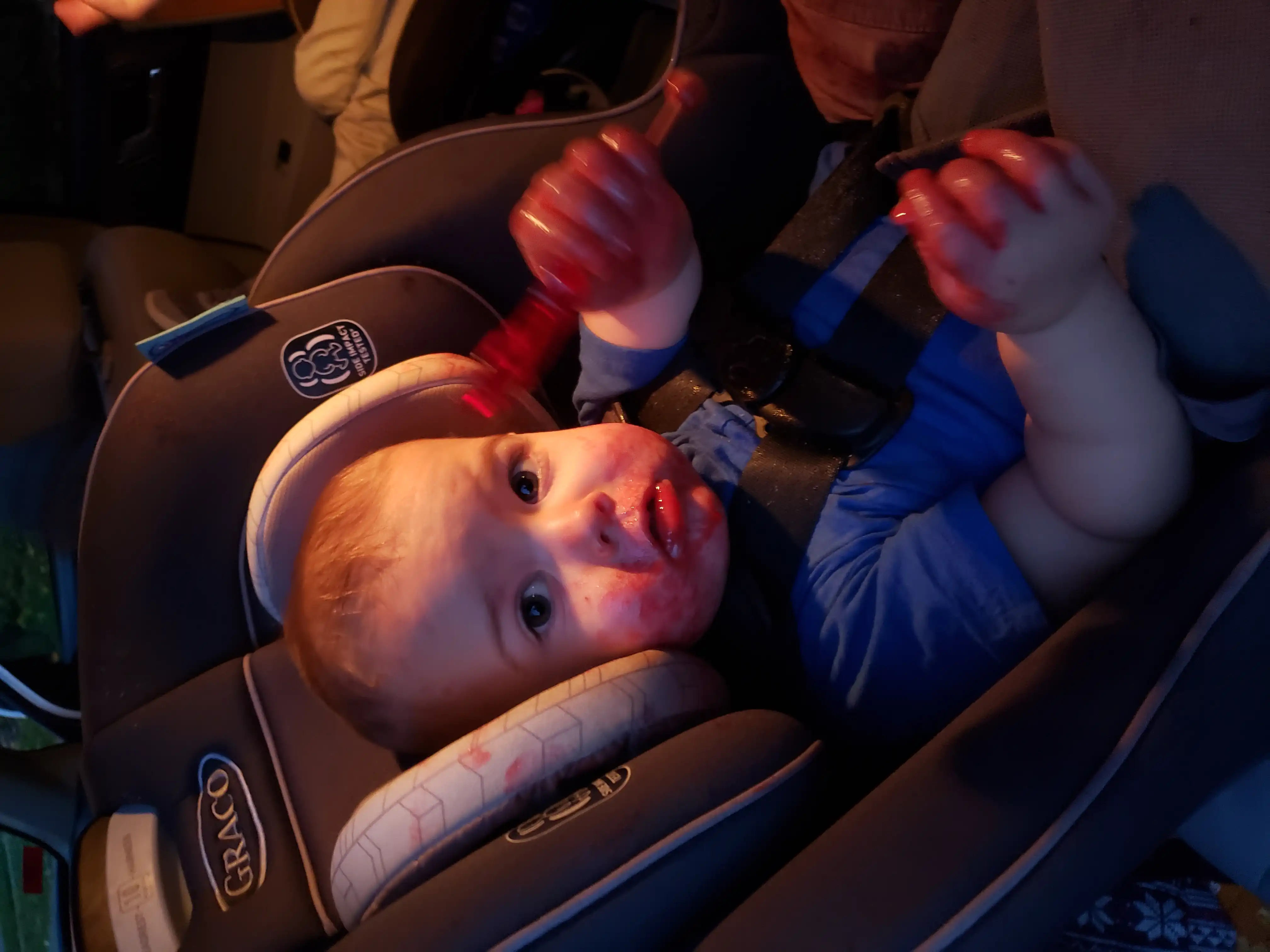Royal in his car seat with red lobster drool from a sucker all over his face.