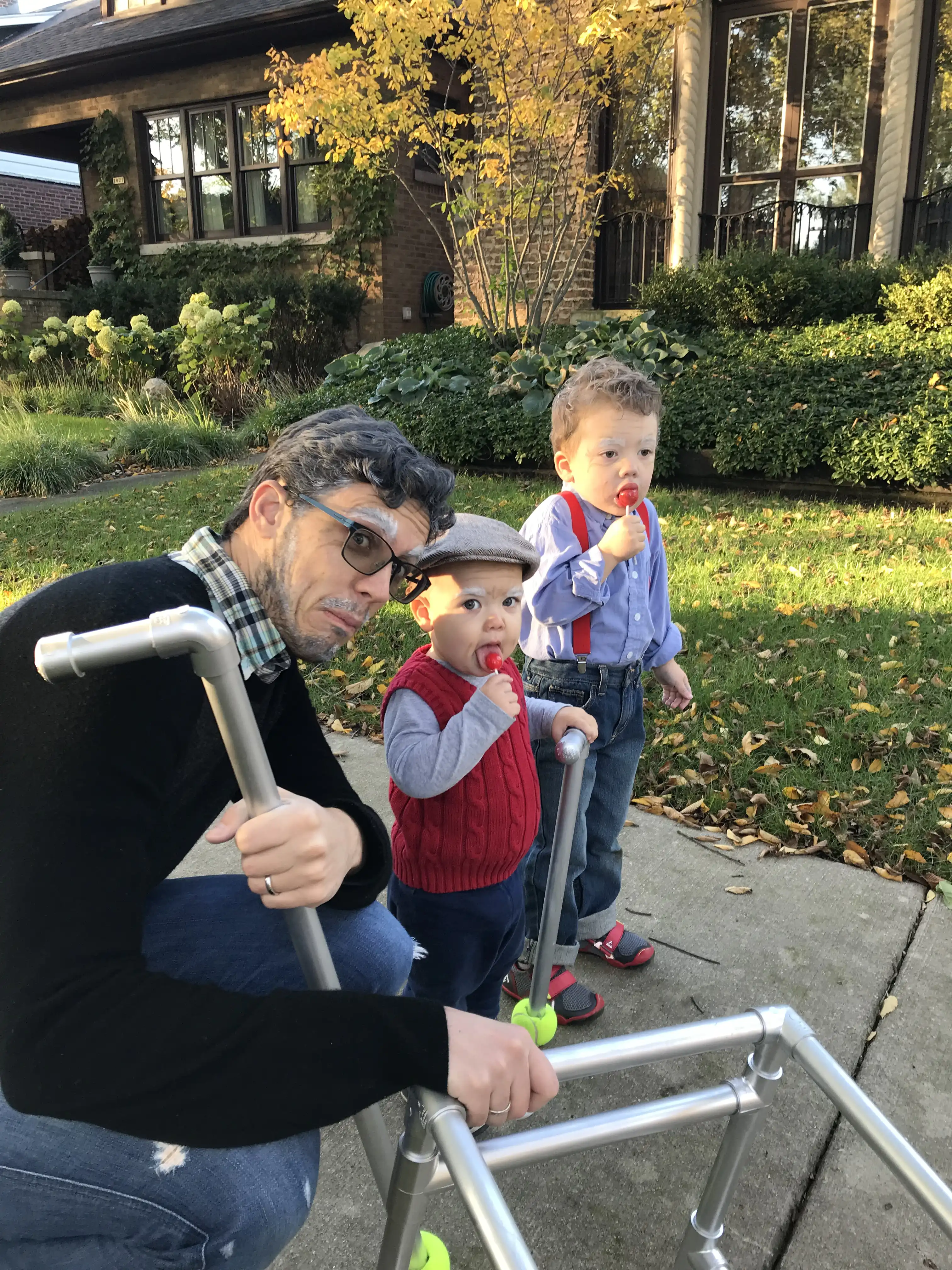 Alex, Graham and Royal wearing their old man costumes. Graham and Royal are sucking on red suckers.