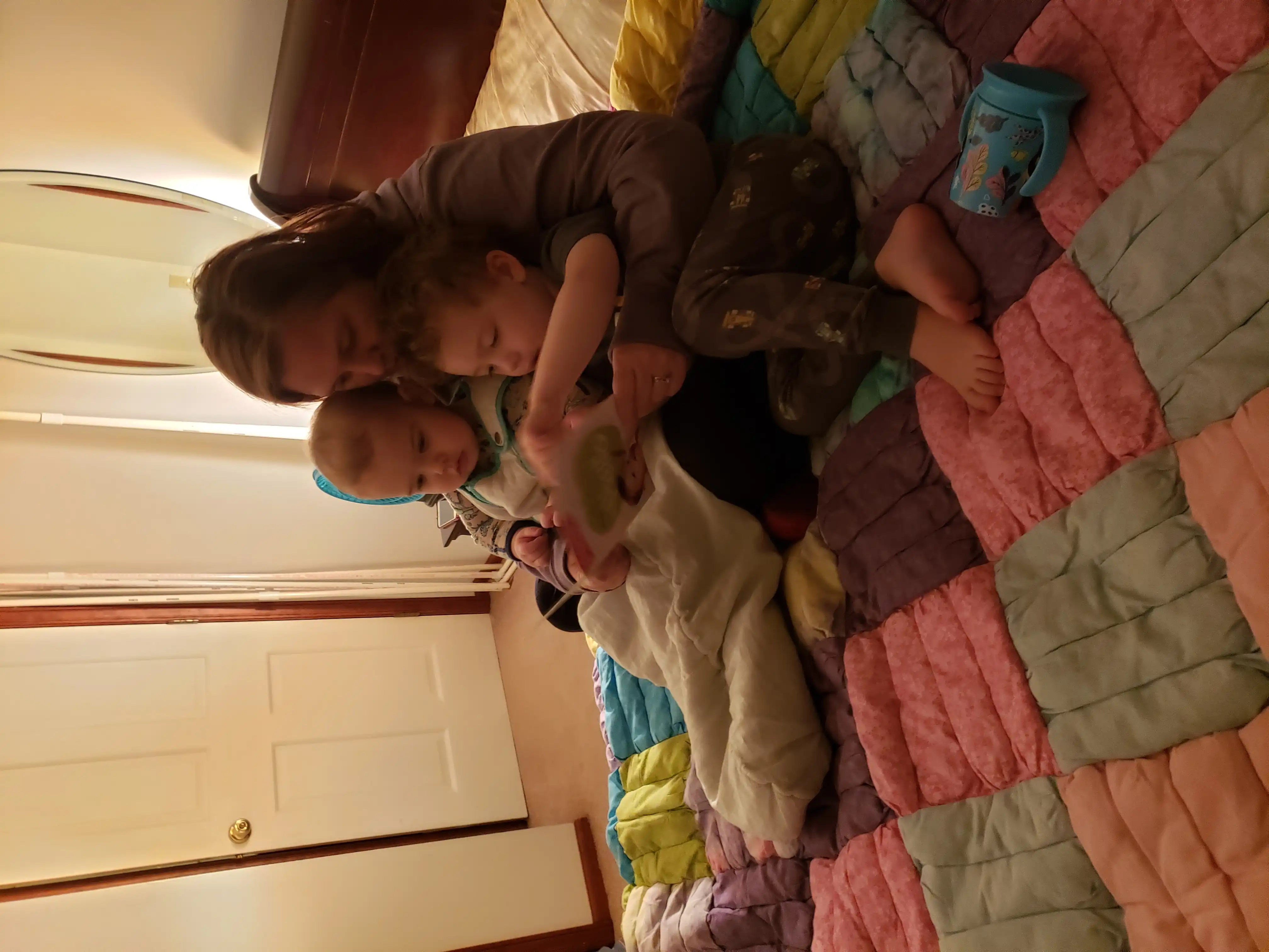 Amie sitting on a quilt, reading a book with Graham and Royal
