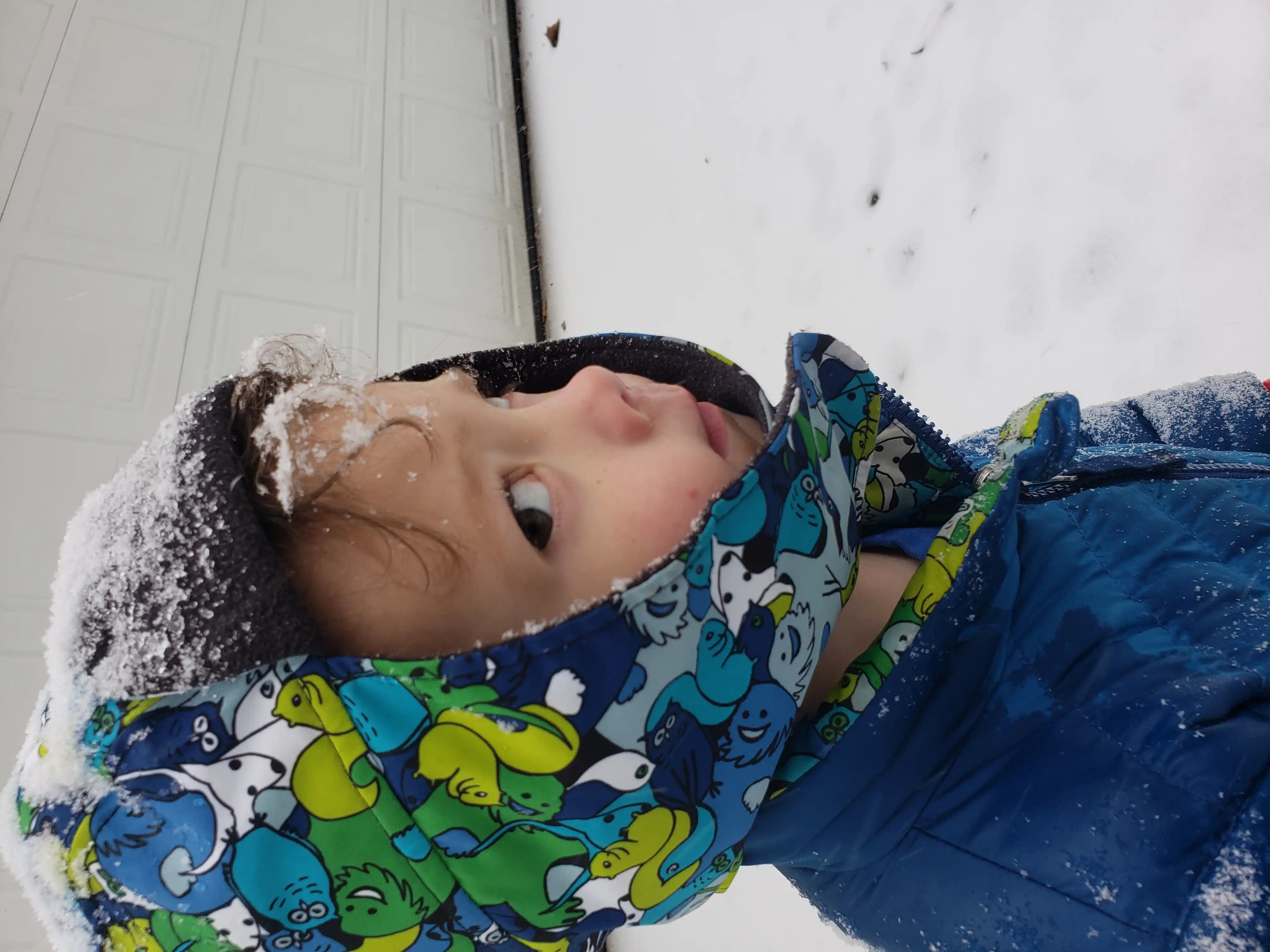 Graham staring at the camera from outside a garage with snow on his coat and hat.