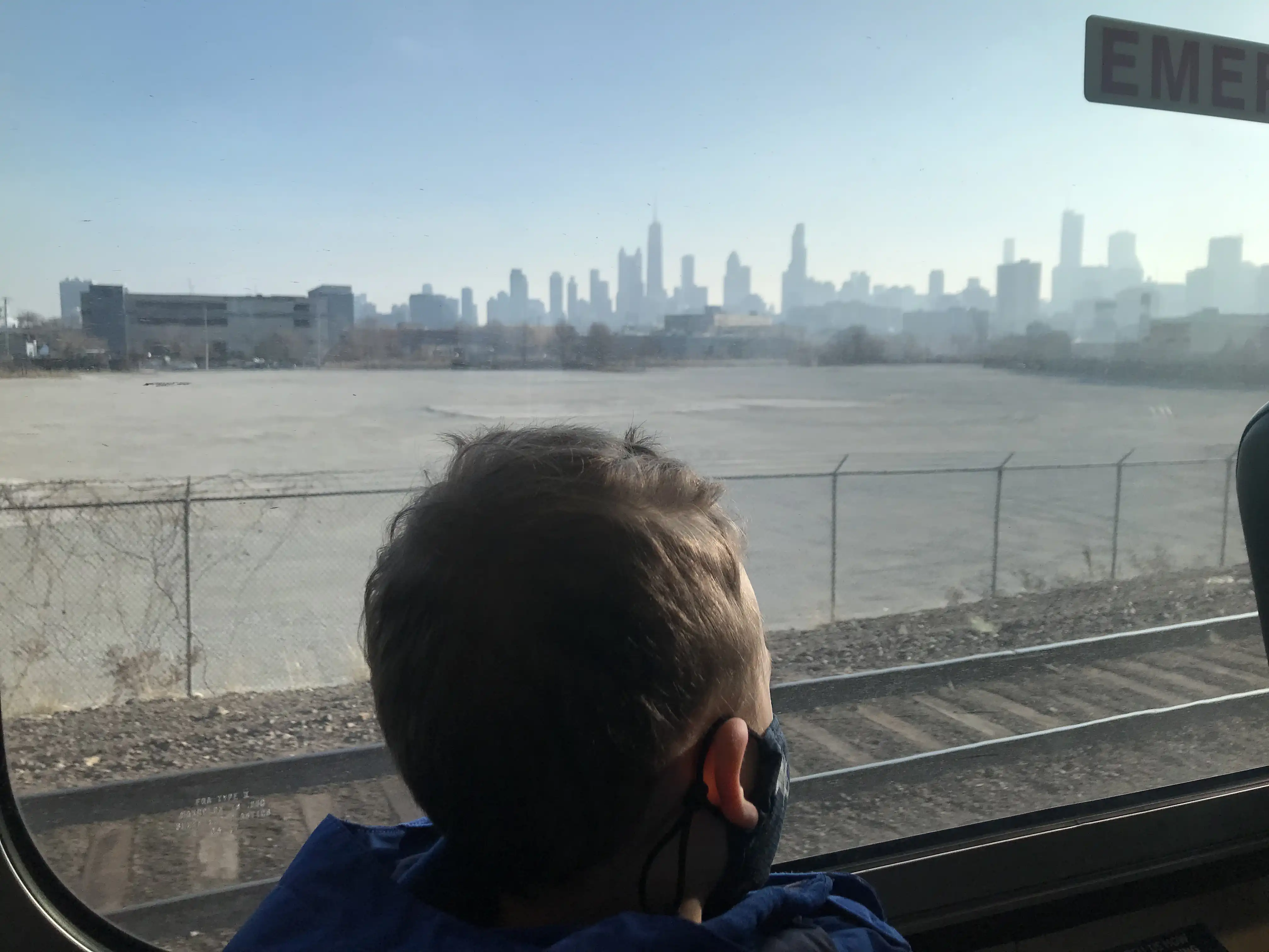 Graham looking out of the Metra train window at downtown Chicago while wearing a COVID mask.