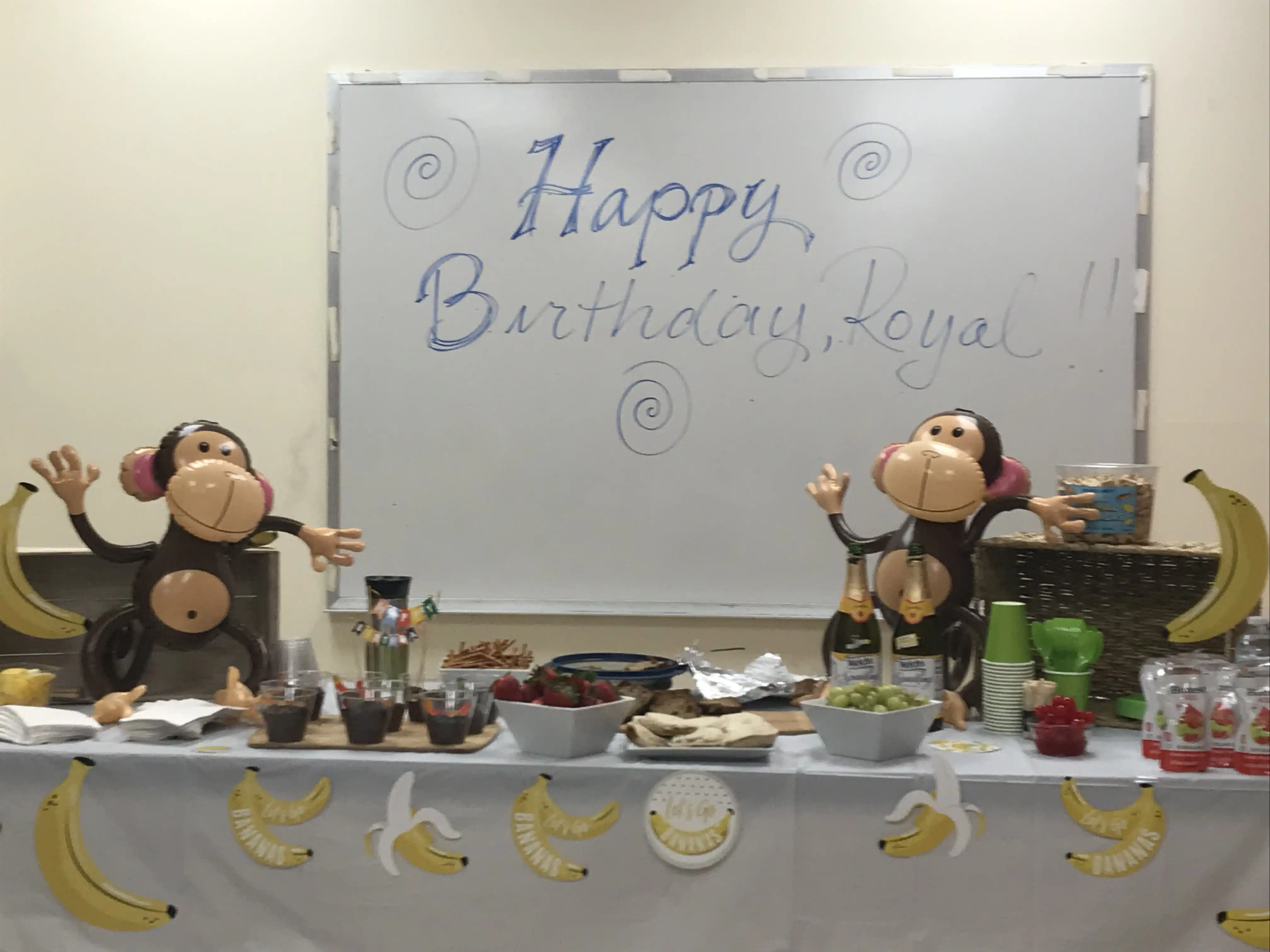 A whiteboard reads, 'Happy Birthday Royal!' with blow-up monkeys and bananas around it.