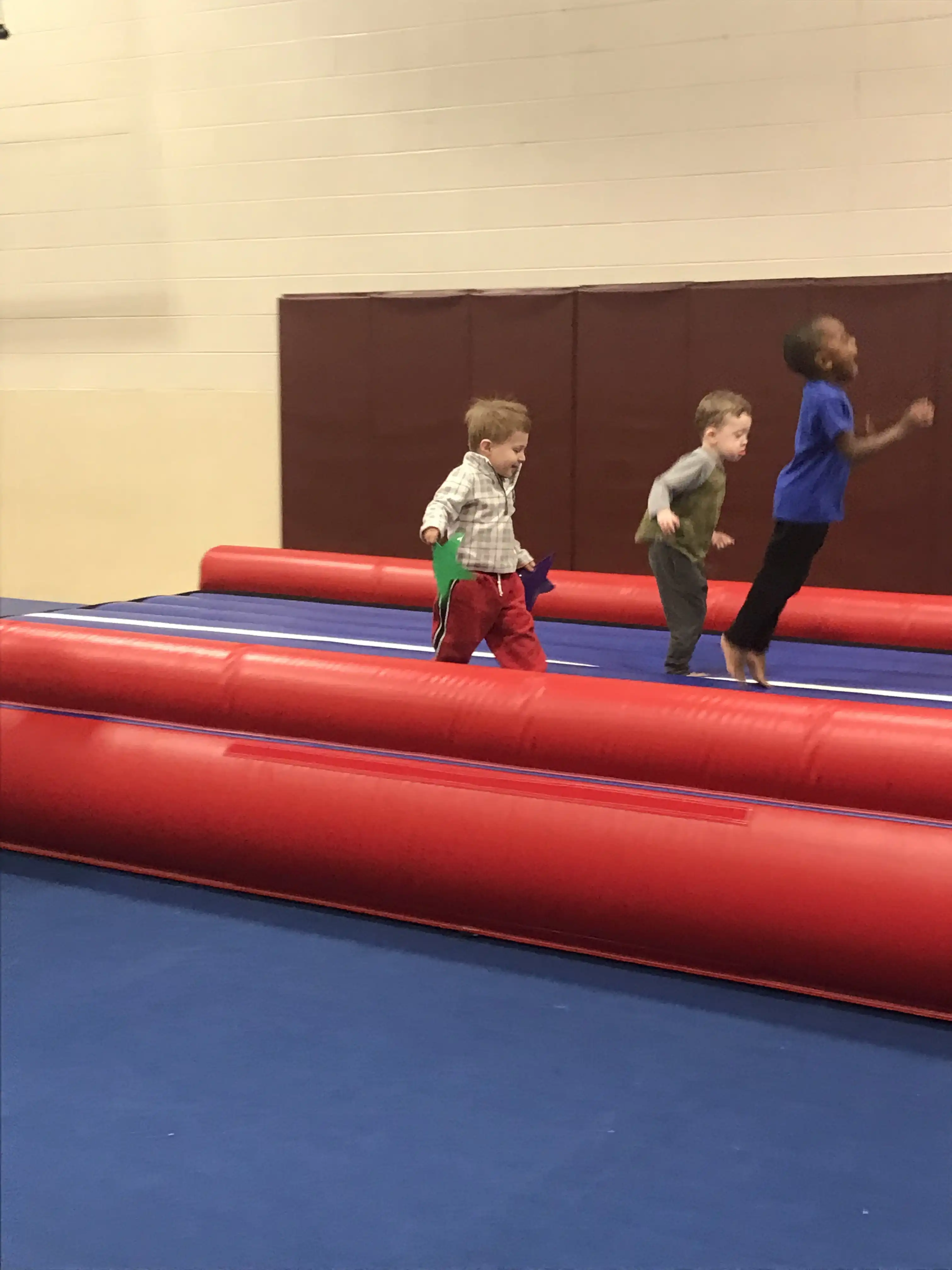 Jotham, Graham and Carter running along a blow-up jumping pad.