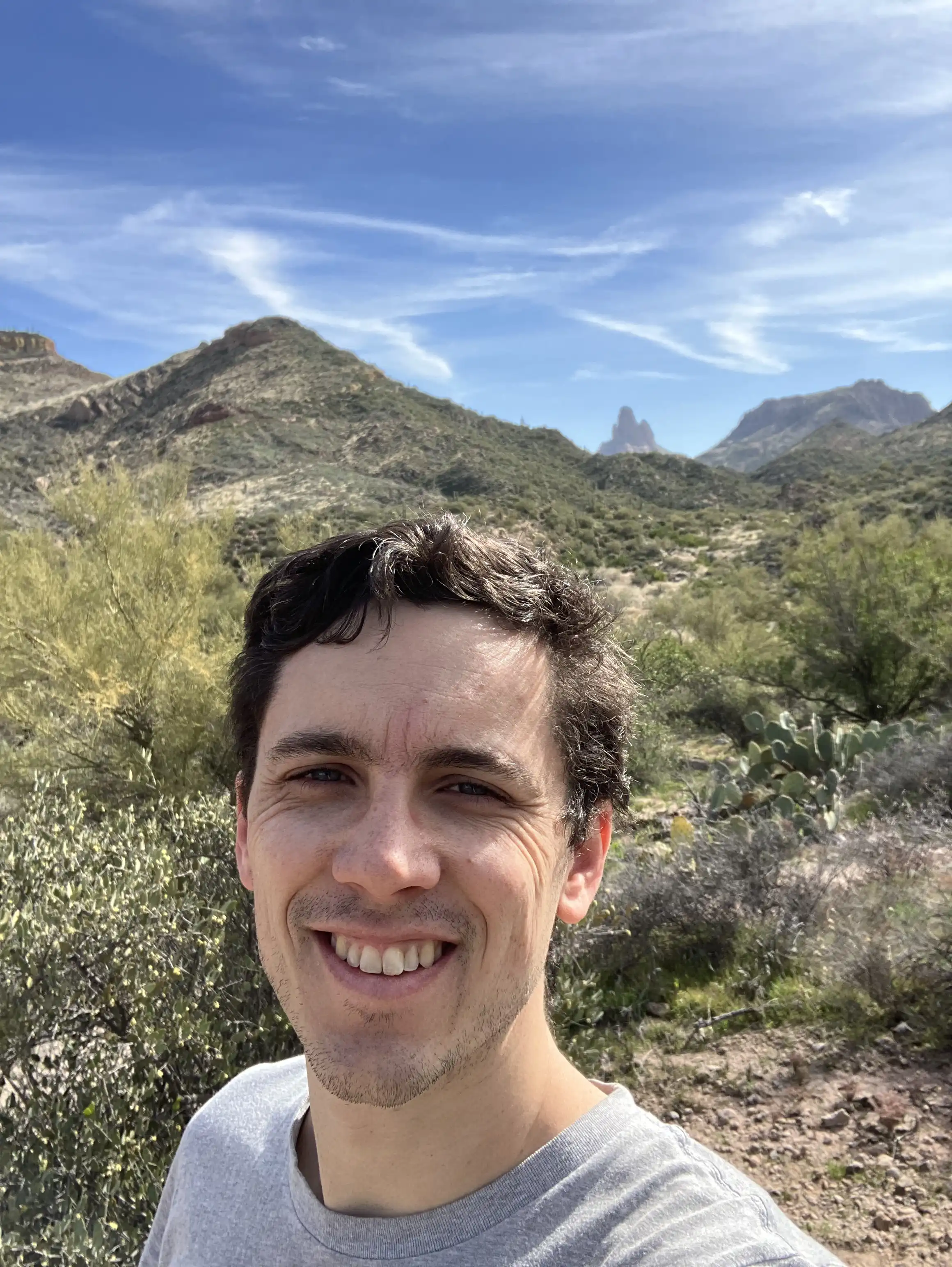 Alex with a view of saguaro cacti, rocks and brush from Tonto National Forest in the background.