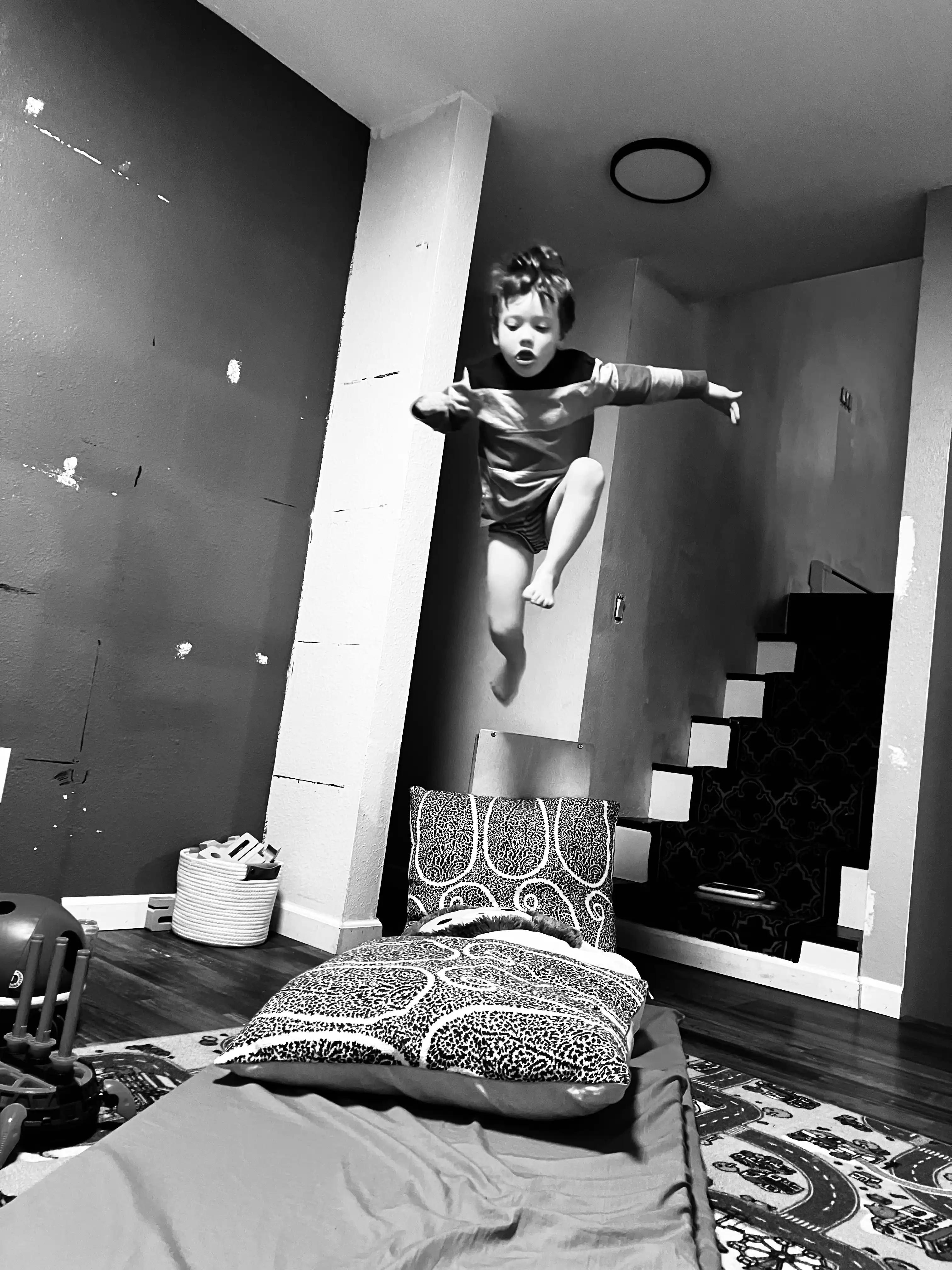Black and white photo of Graham in mid-flight, leaping onto a pile of pillows.