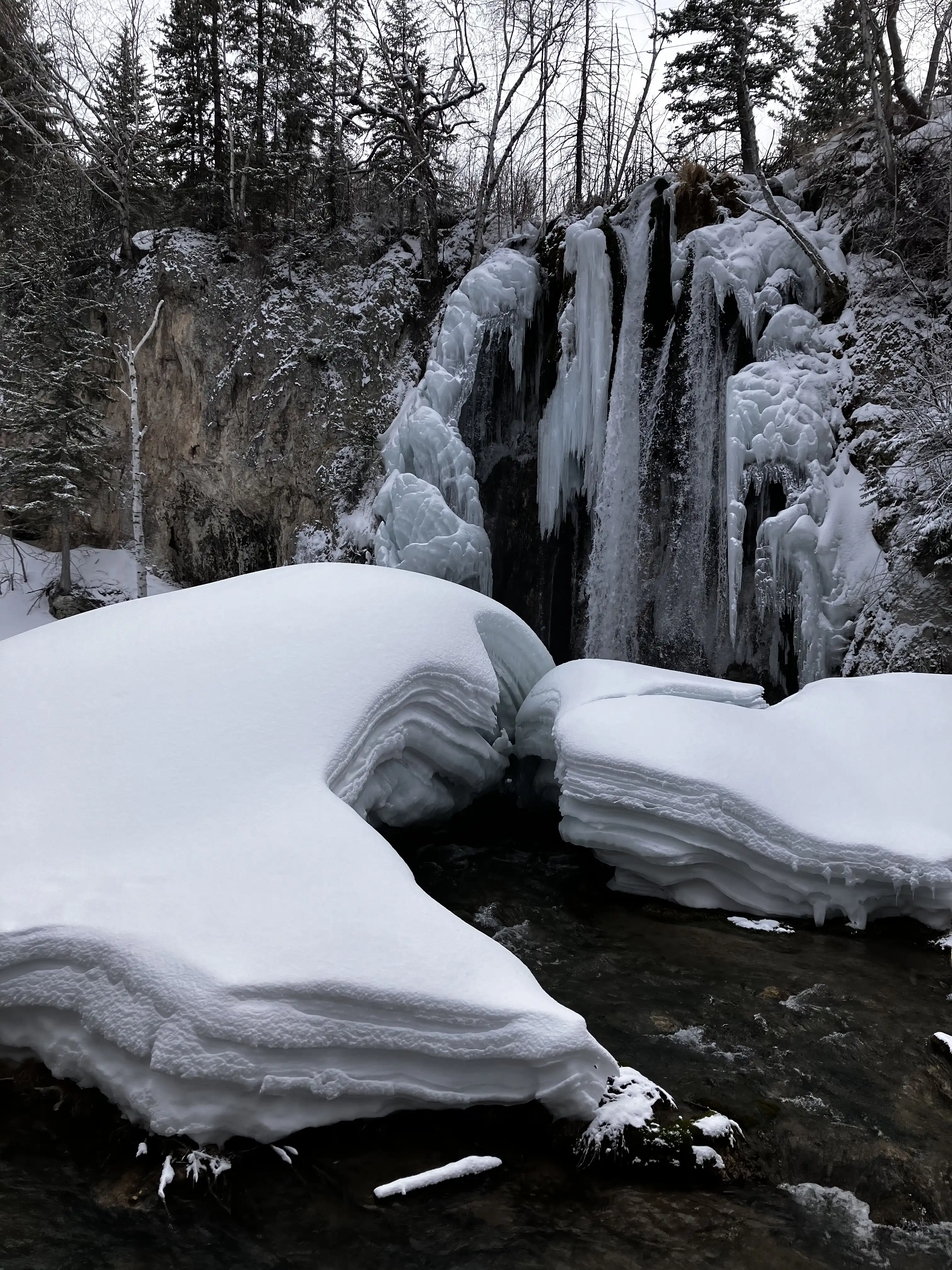 An ice-covered waterfall. The ice spreads like angel's wings to the left and right, and there's a canyon cut through the snow.