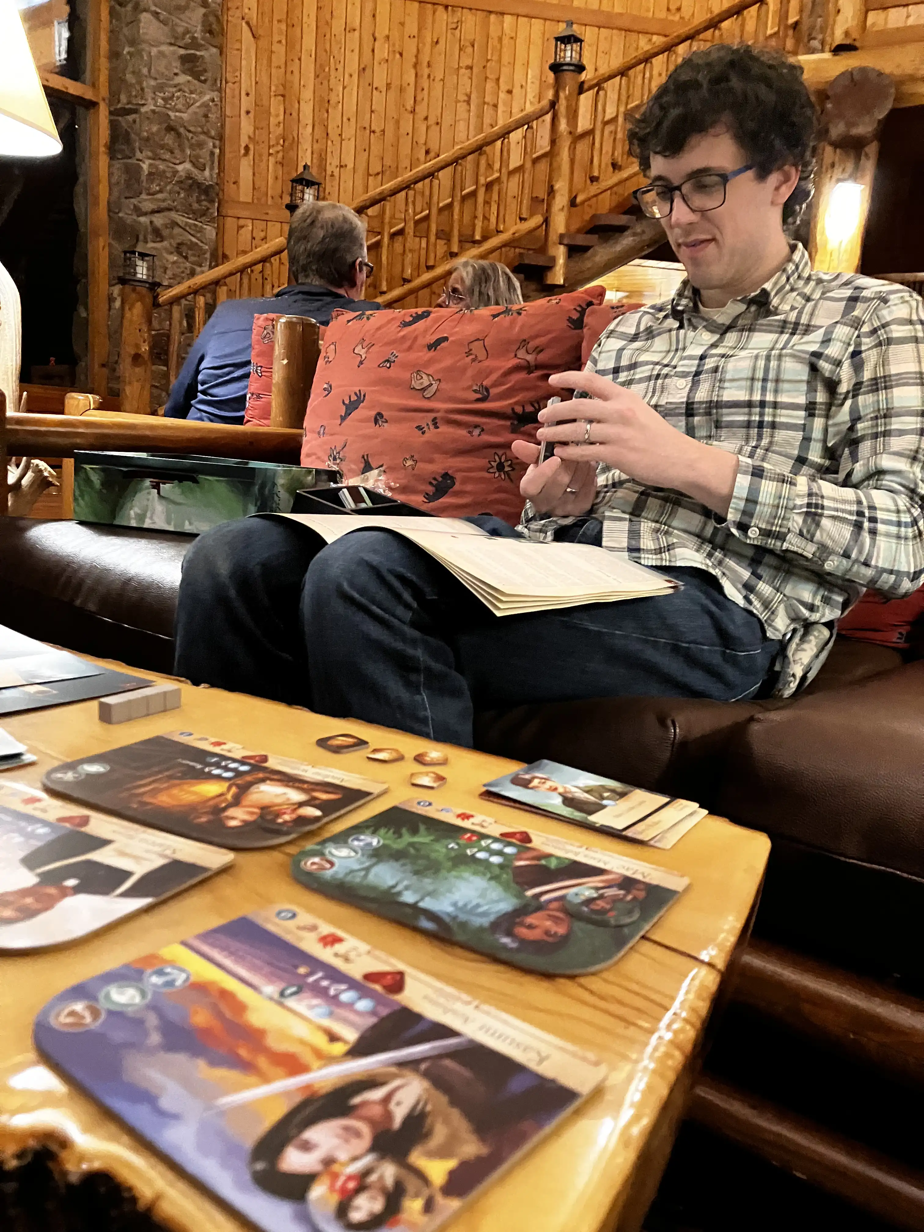 Alex playing his new board game in the wooden public lodge area.