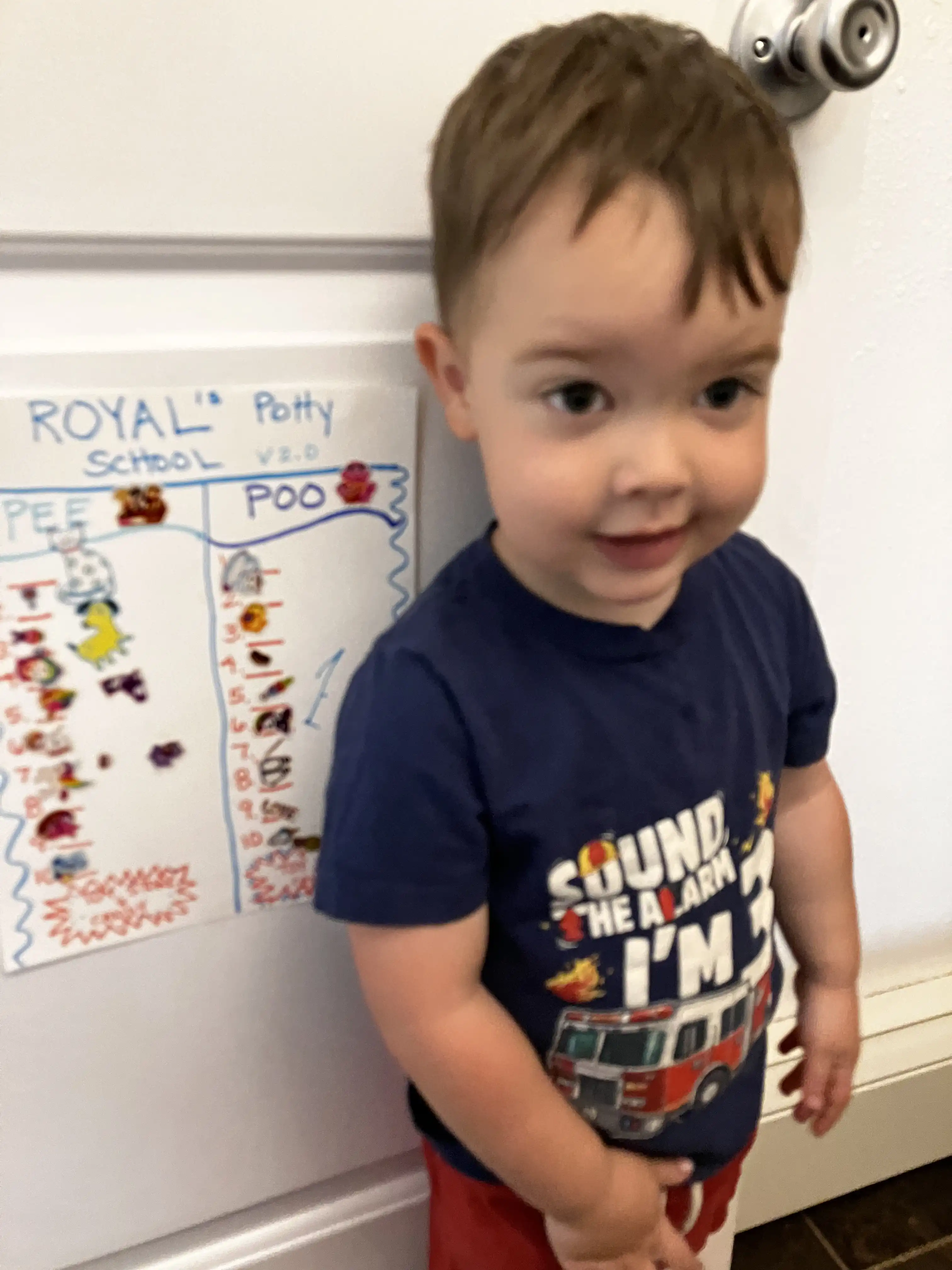 Royal standing next to his potty training chart with all the stickers filled in.