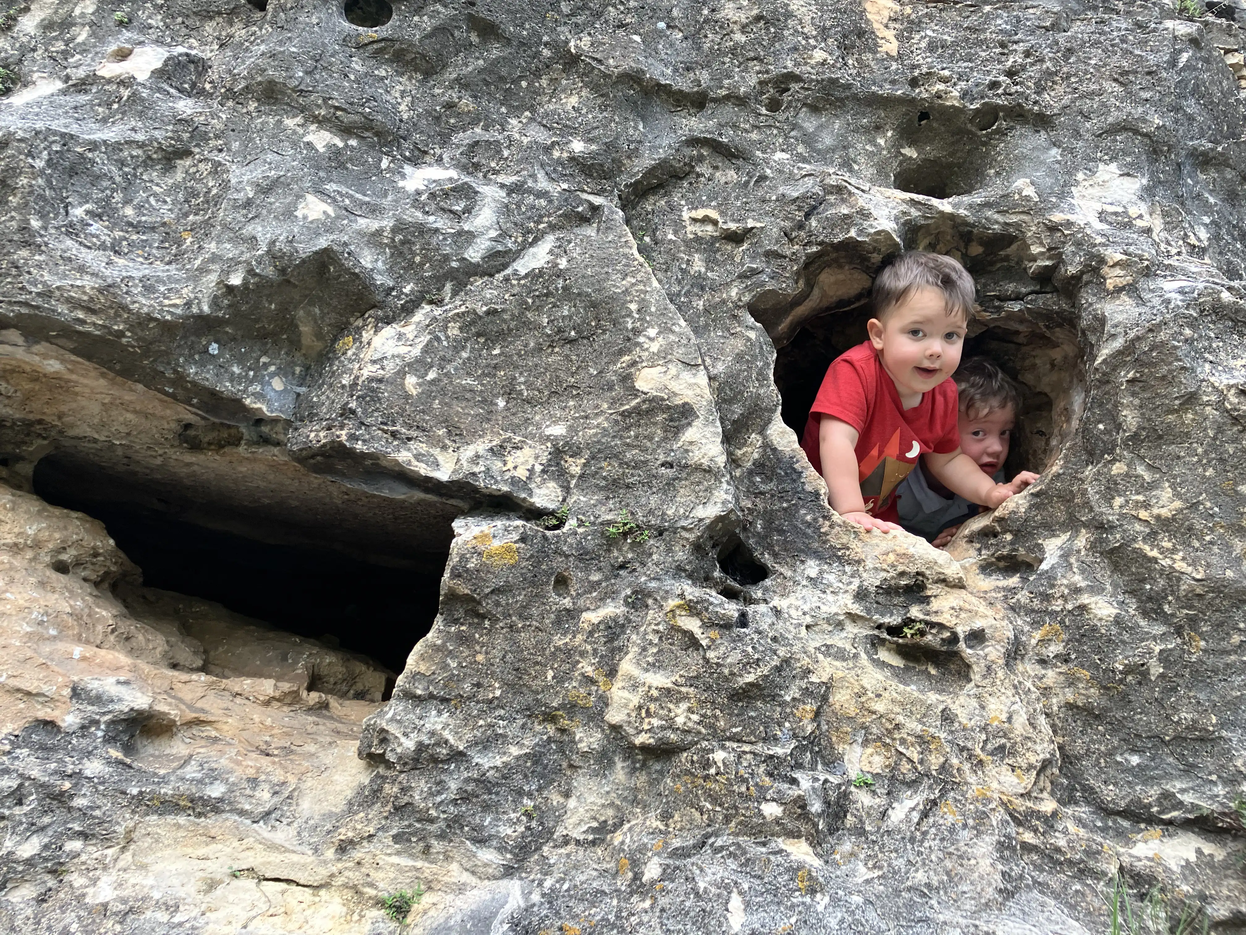 Graham and Royal peeking out from a small cave high up on a rock face.