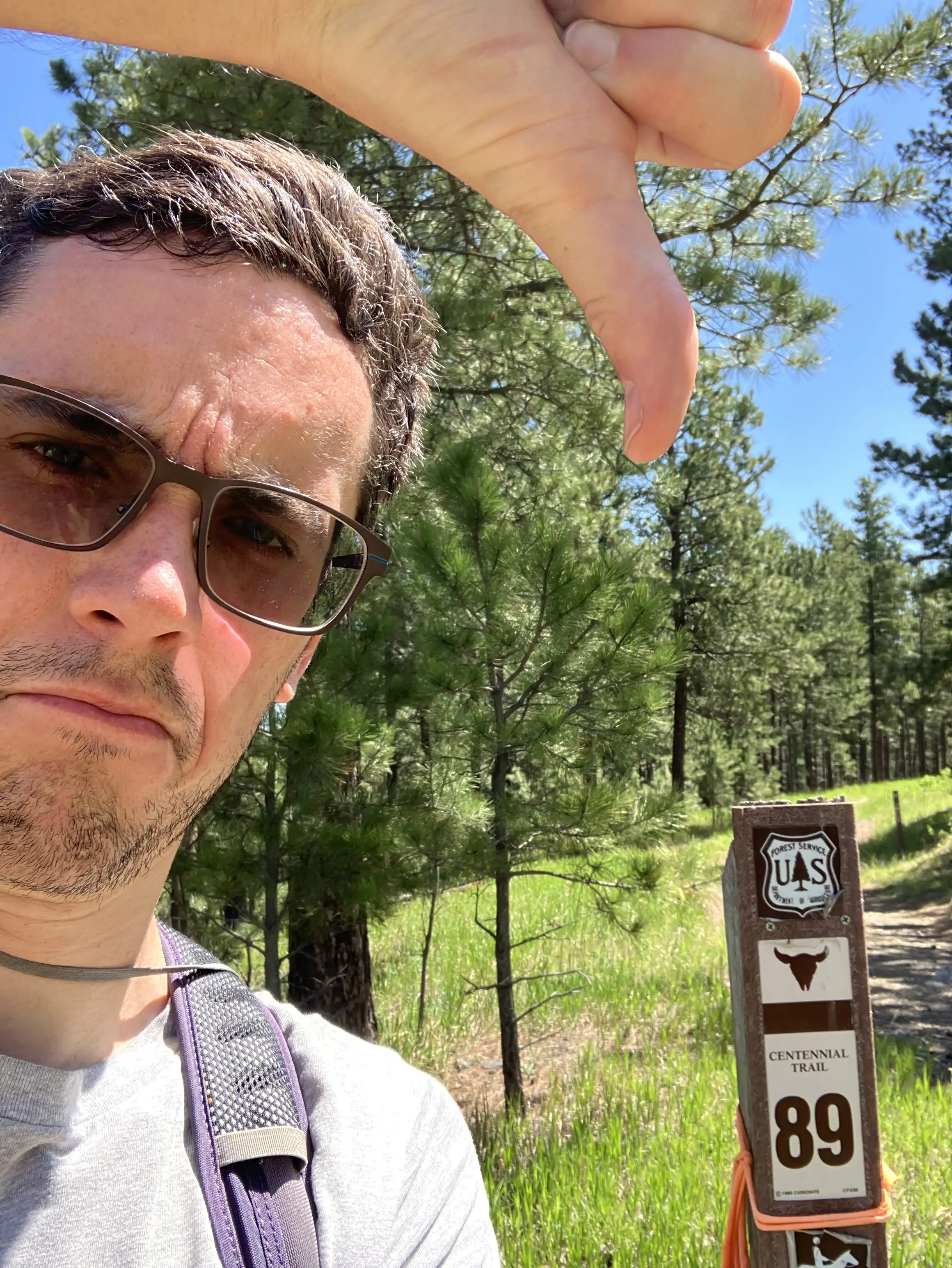 Alex giving the thumbs-down to a sign that poorly denotes the Centennial Trail horse bypass