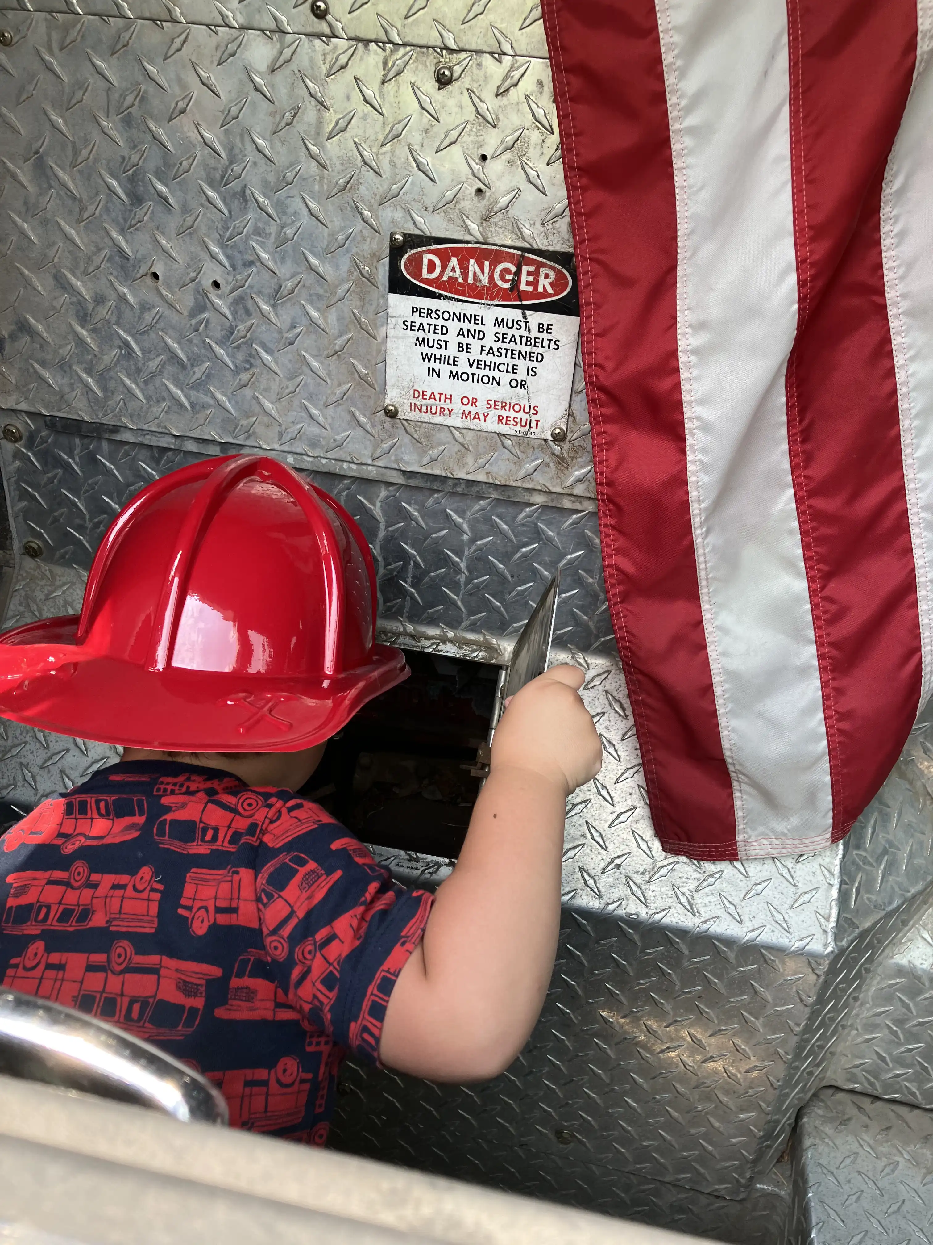 Royal wearing a plastic fireman's hat, looking into a steel compartment.