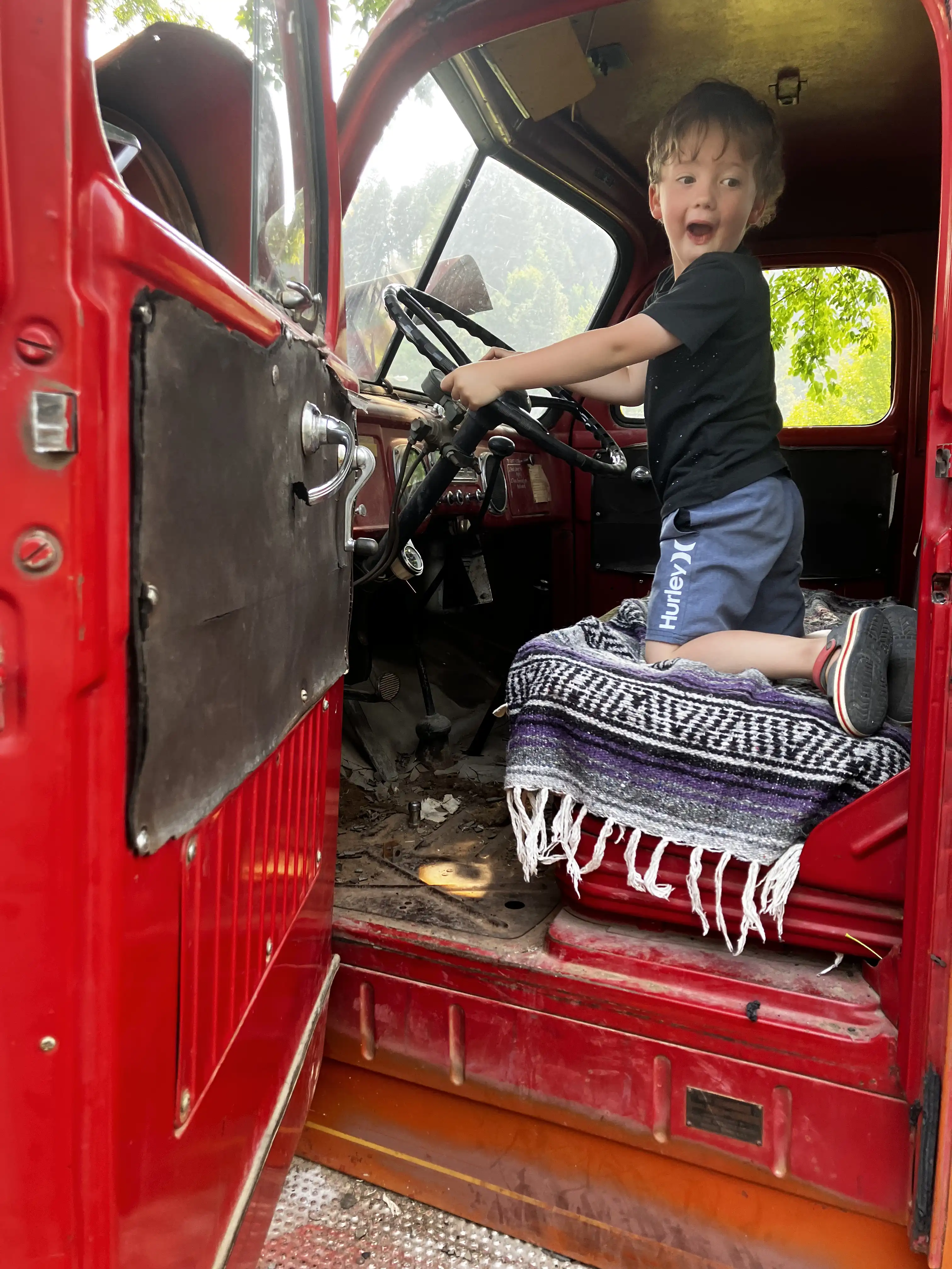 Graham ecstatically smiling from the front driver's seat of an old firetruck.