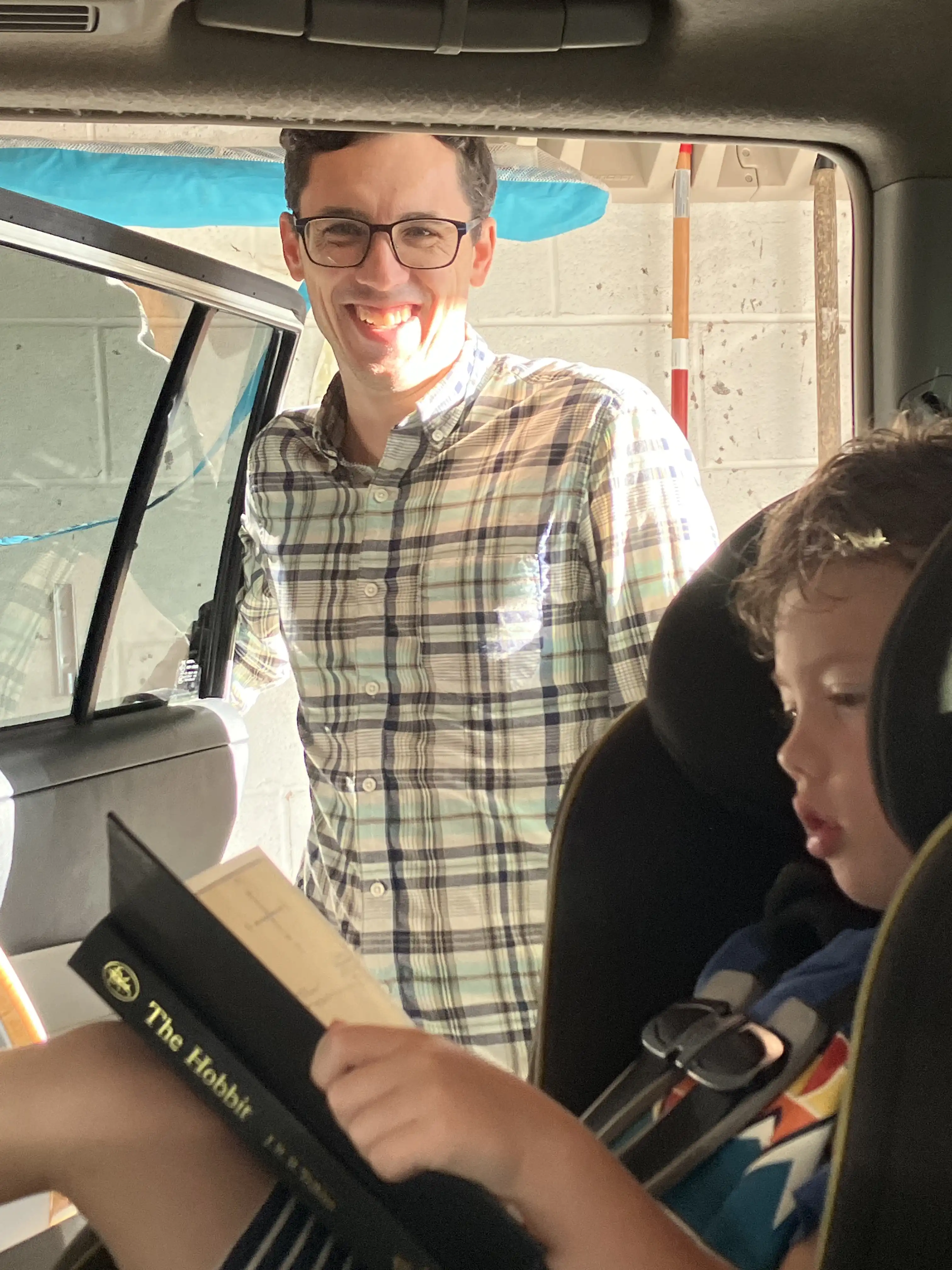 Graham in the car reading The Hobbit with Alex smiling proudly behind.