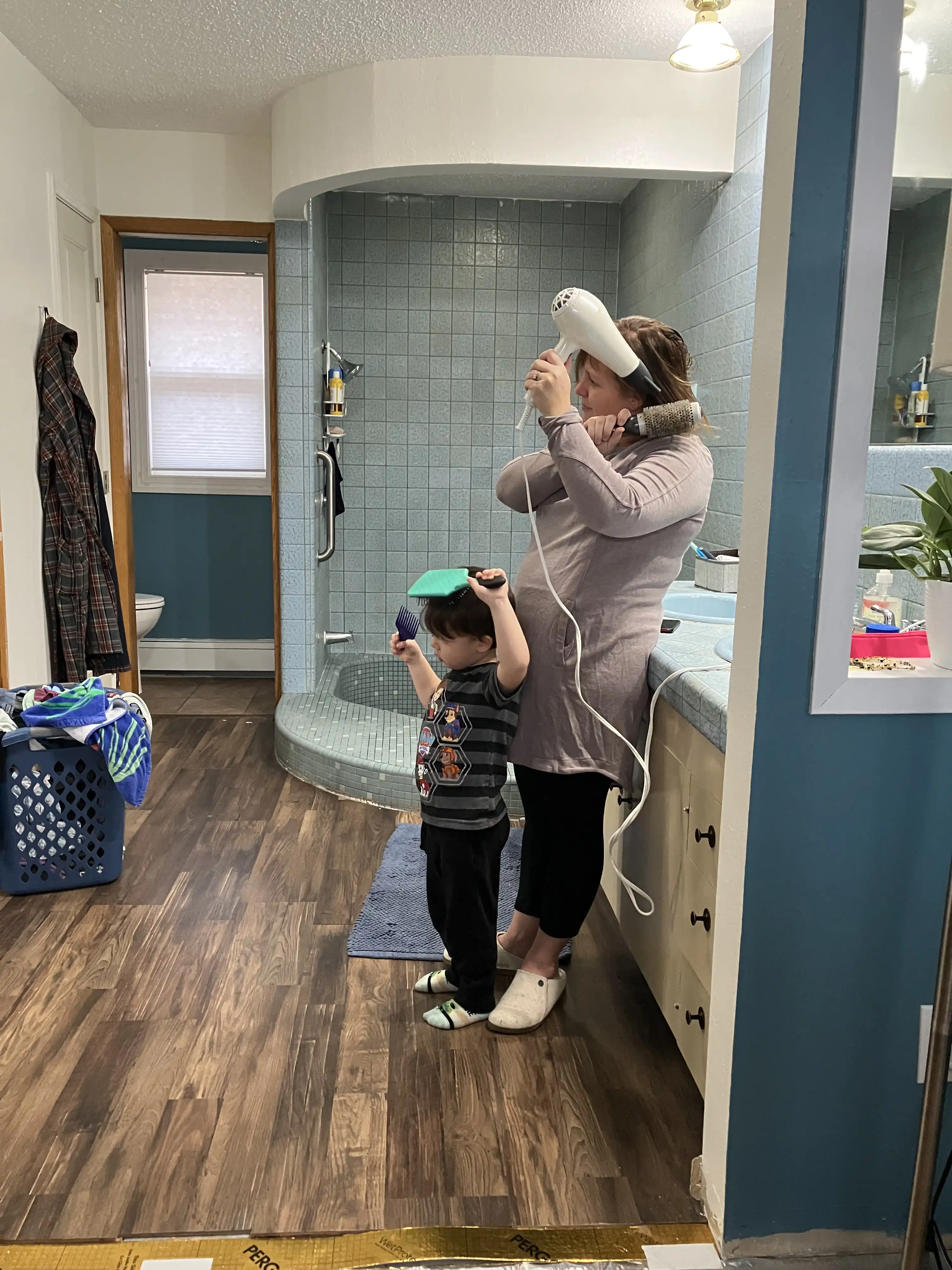 Amie and Royal brushing their hair, both looking intently into the mirror.
