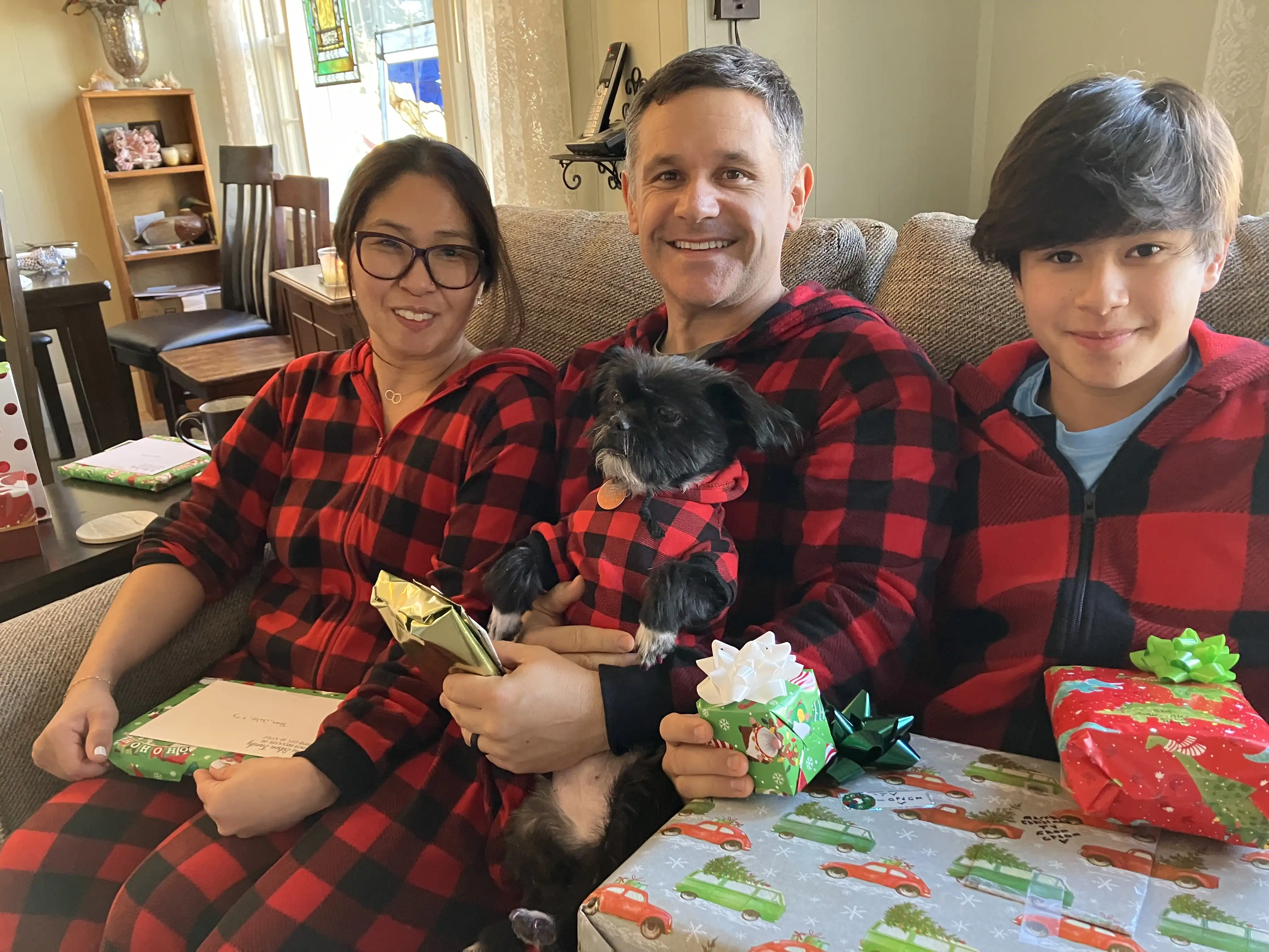 Julie, Tom, Panda and Ty in matching pajamas holding their Christmas gifts